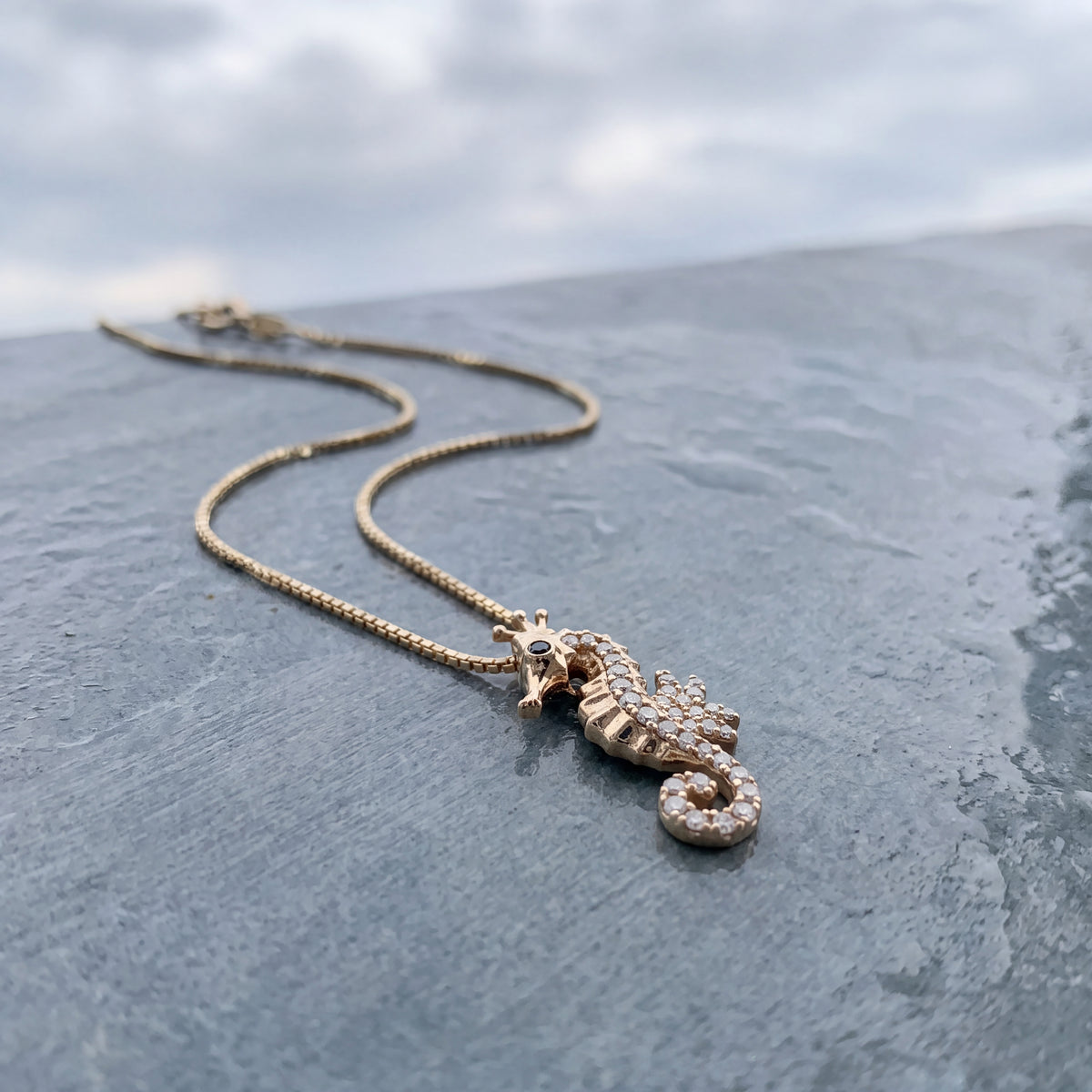 Yellow gold seahorse pendant with a sapphire eye and small diamonds
