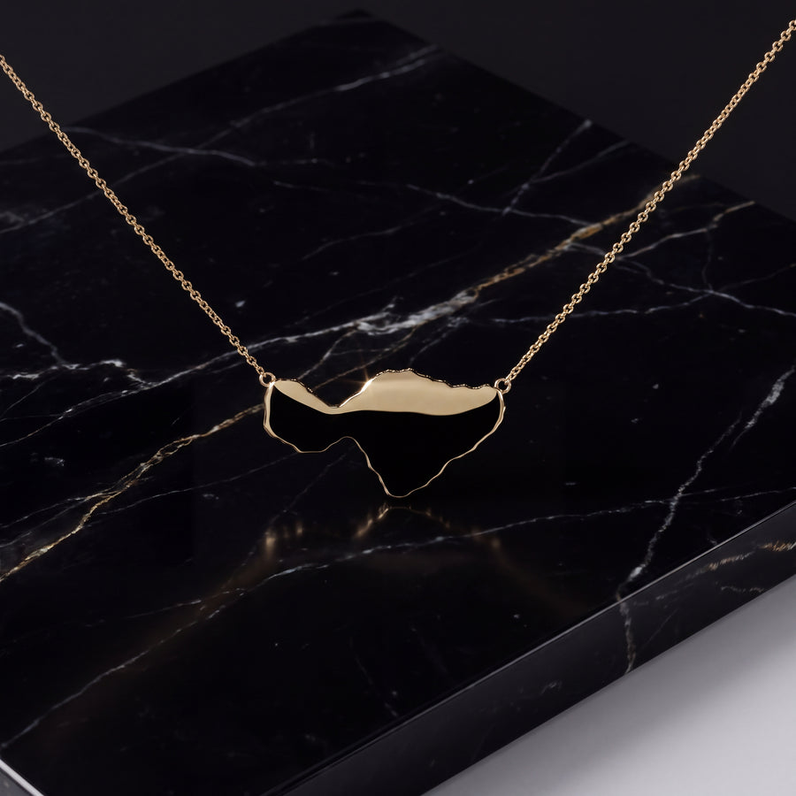 A polished gold island silhouette on a fine chain.