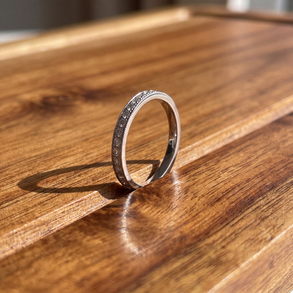 Slim band with a row of small round diamonds between milgrain edges