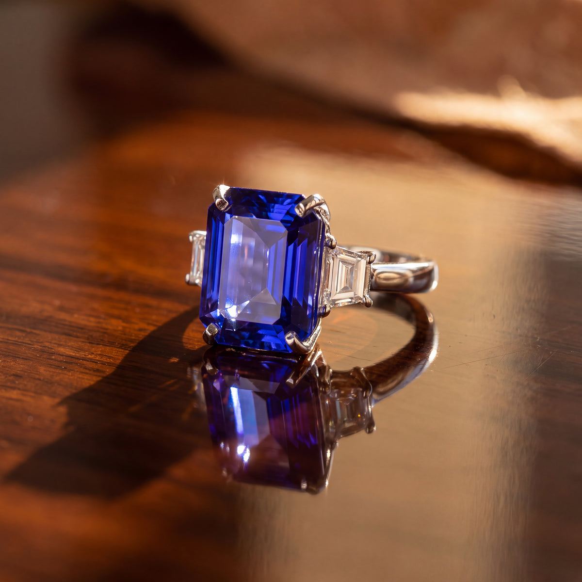 Emerald-cut tanzanite between two trapezoid diamonds, in white gold
