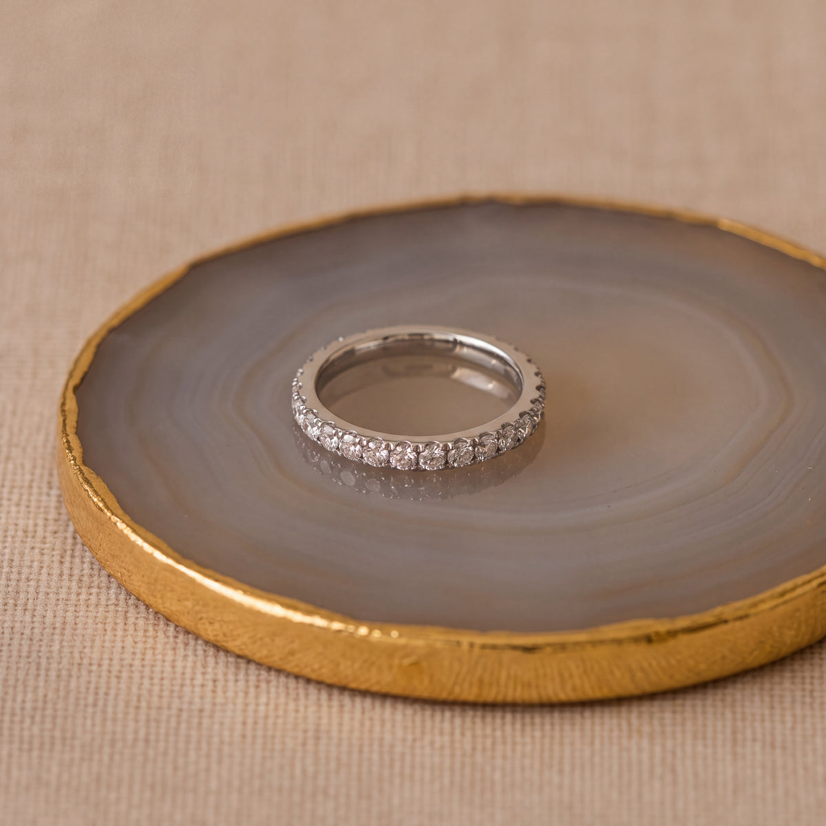 Slender white gold band with a row of round diamonds in U-shaped prong settings