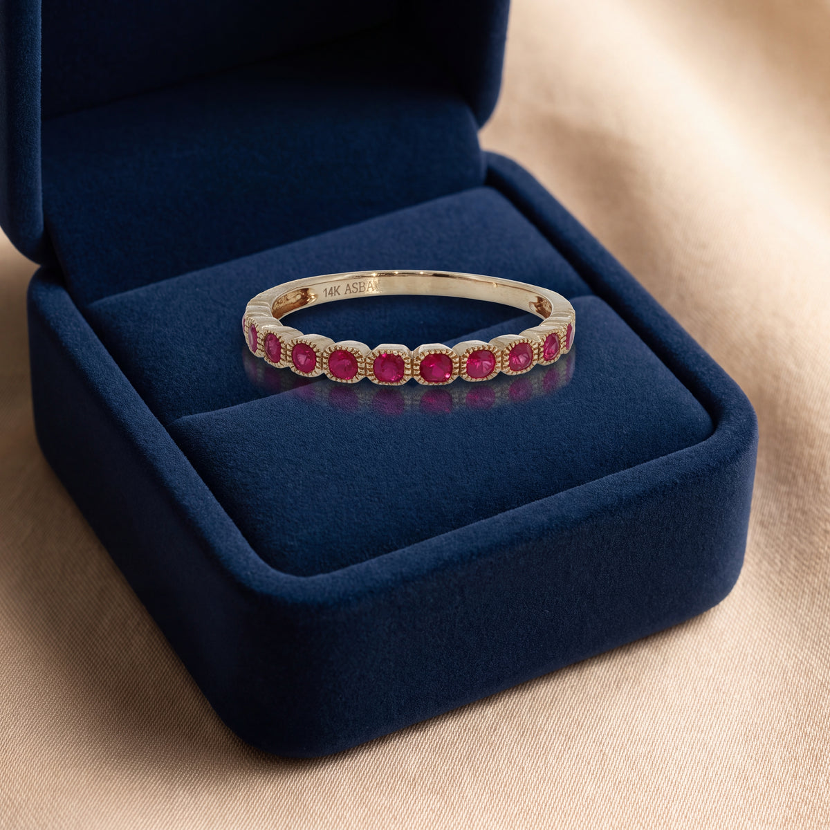 Yellow gold half eternity ring of rubies in milgrain bezels