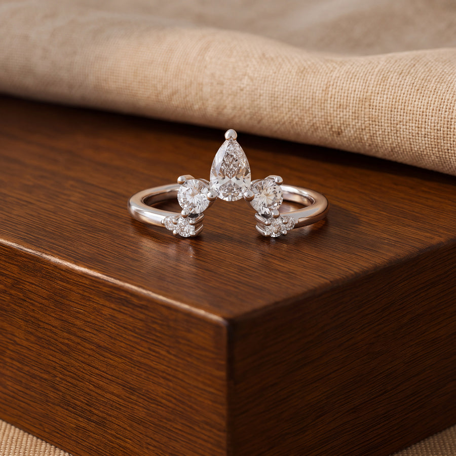 Curved white gold guard ring with a pear-shaped center diamond flanked by round diamonds