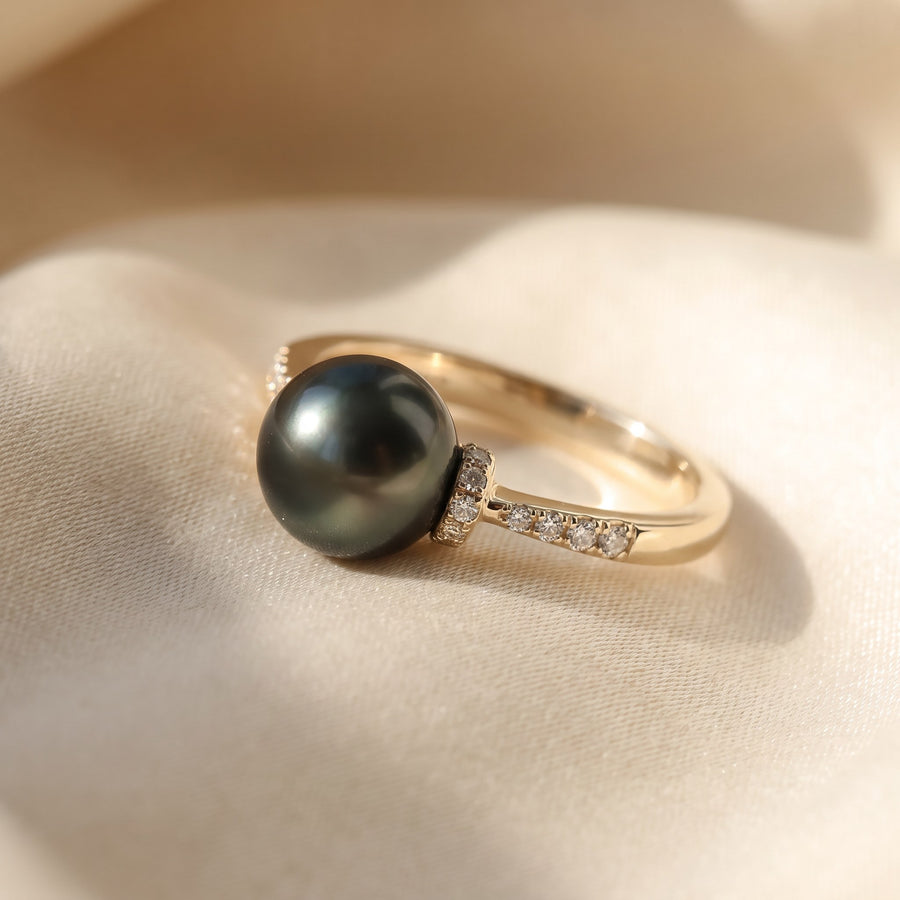 Black pearl ring on a yellow gold band with diamond shoulders