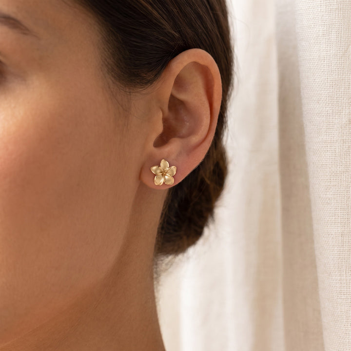Brushed Plumeria Flower Stud Earrings in 14K Yellow Gold, worn