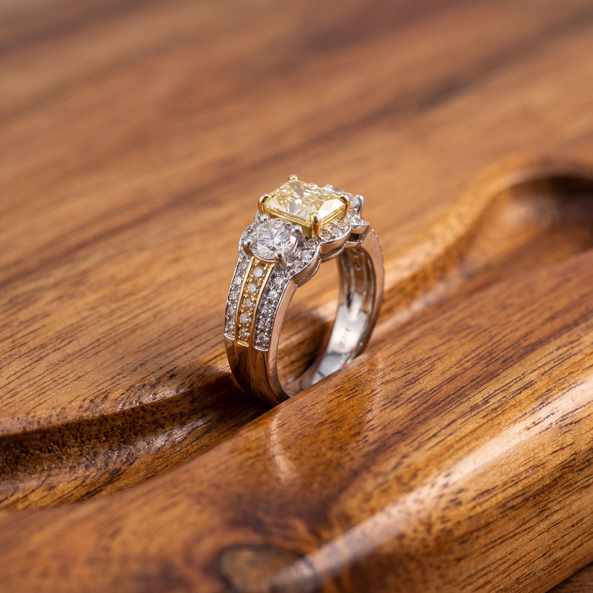 Fancy yellow diamond ring with two round diamonds on a wide pavé band