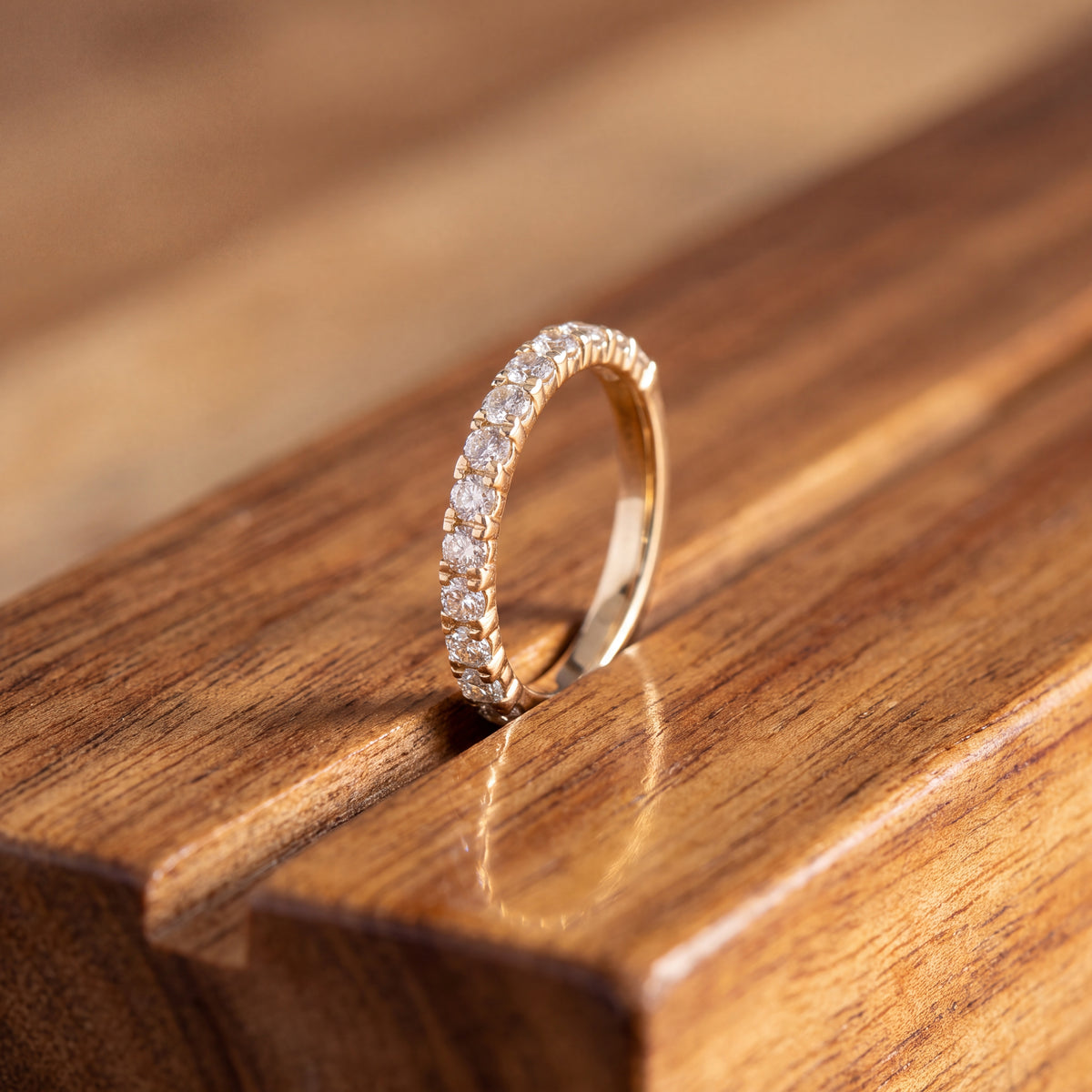 Slim yellow gold band with a row of round diamonds in shared U-shaped prong settings