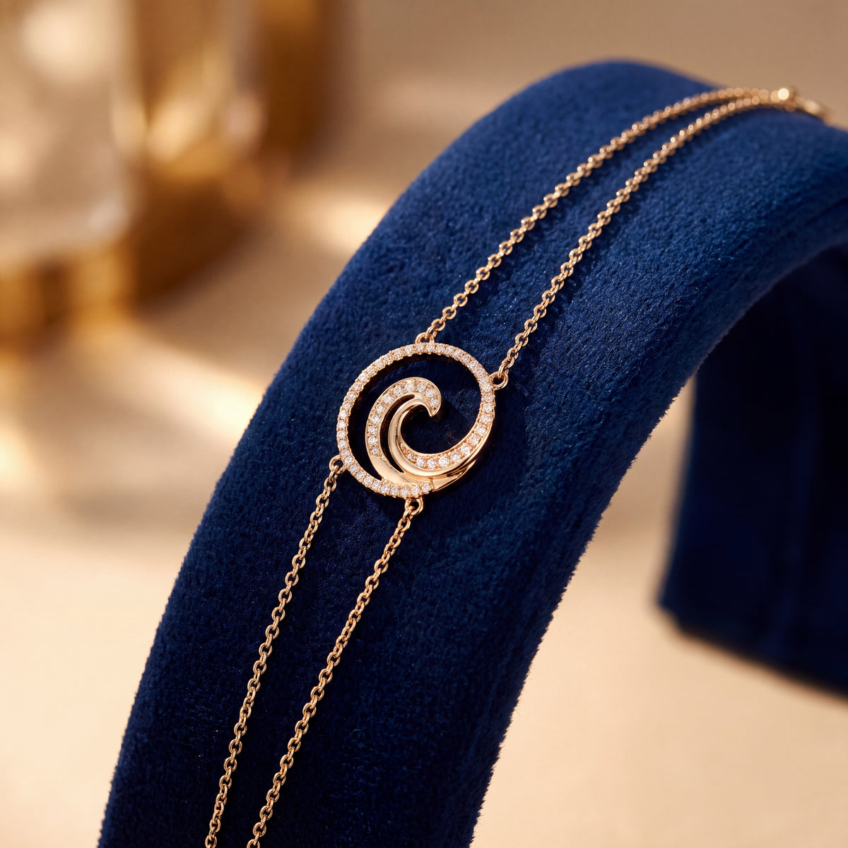 A gold chain bracelet with a diamond-set spiral wave, laid across navy velvet.