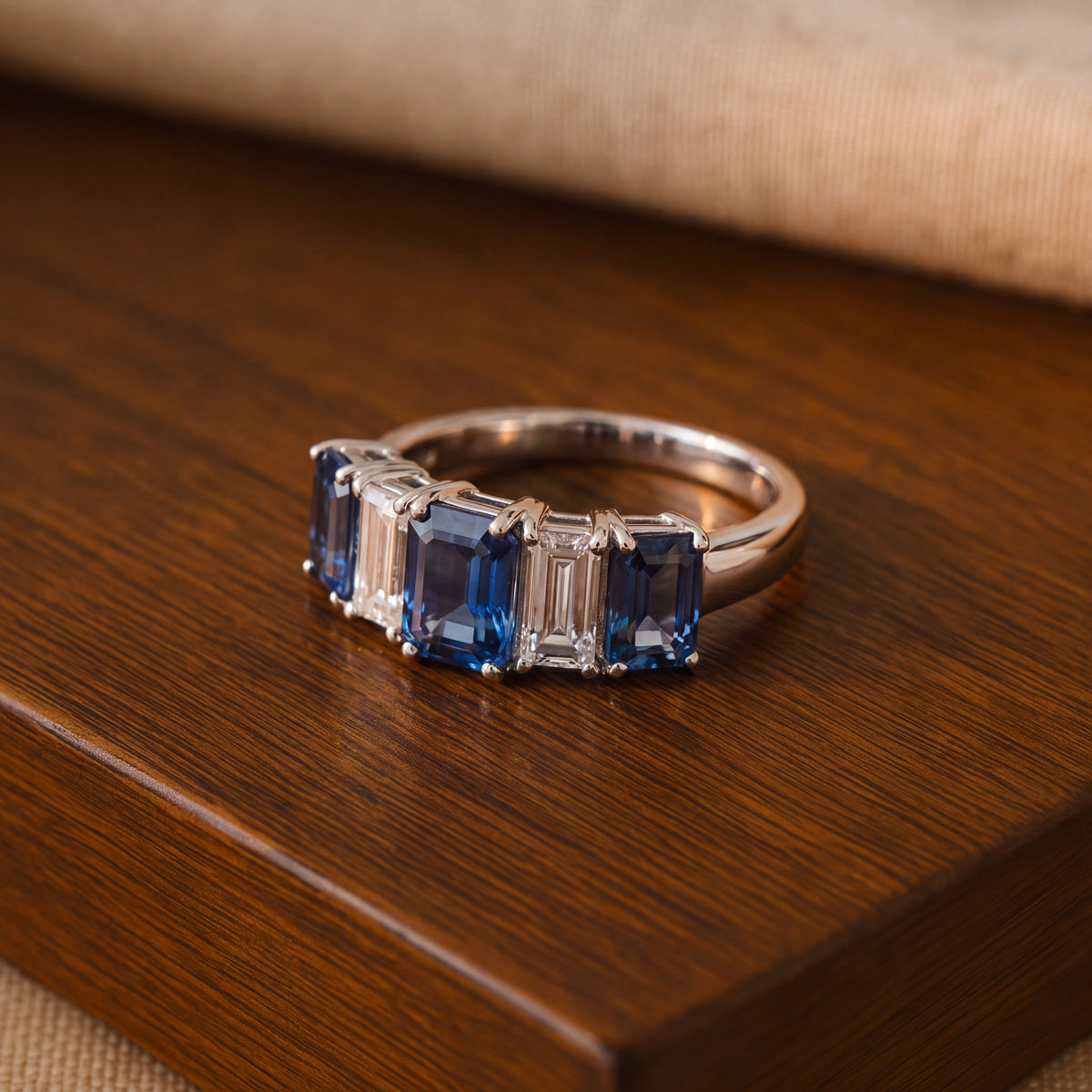 White gold five-stone ring of emerald-cut blue sapphires and diamonds