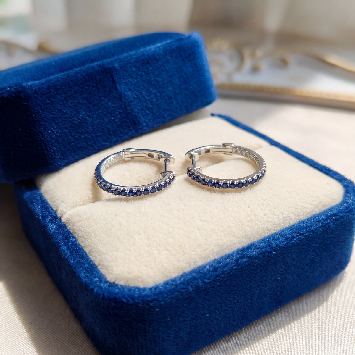 Pair of white gold hoop earrings lined with blue sapphires