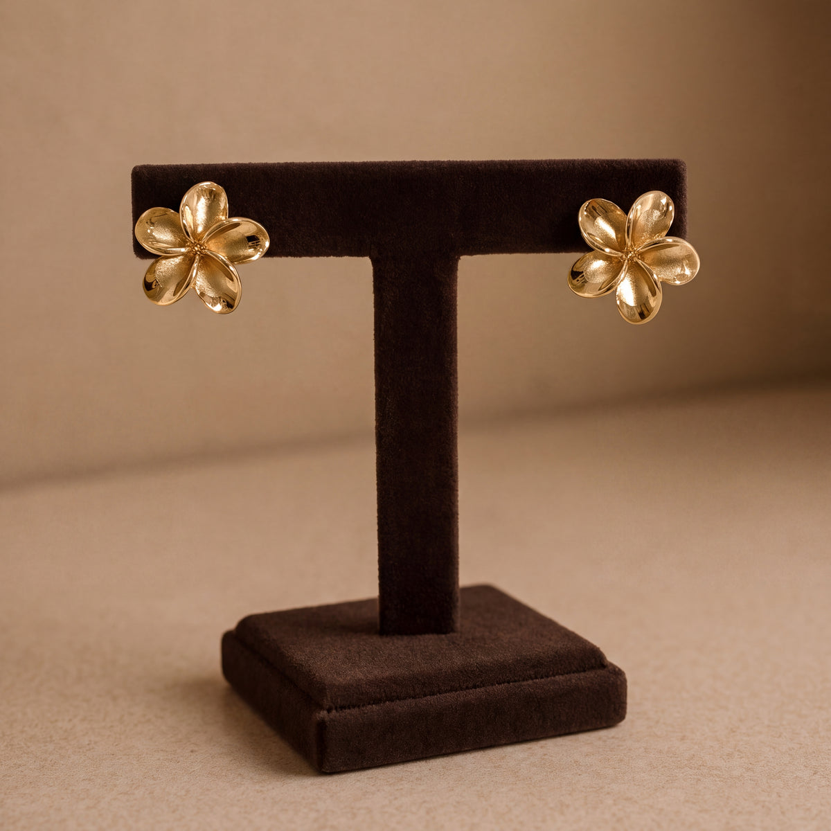Pair of yellow gold five-petal plumeria stud earrings with a smooth polished finish