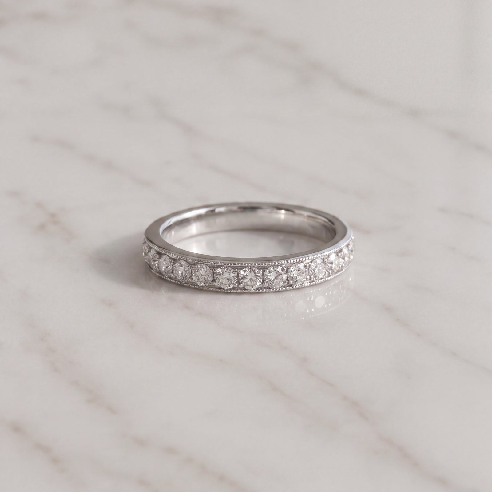 A white gold pave band traced with milgrain along its upper and lower edges.