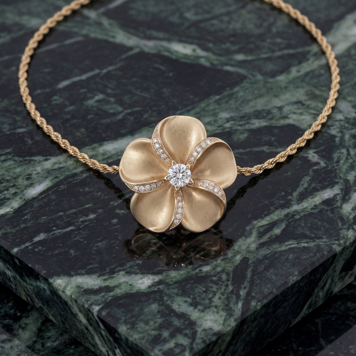 Brushed yellow gold plumeria pendant with a diamond center