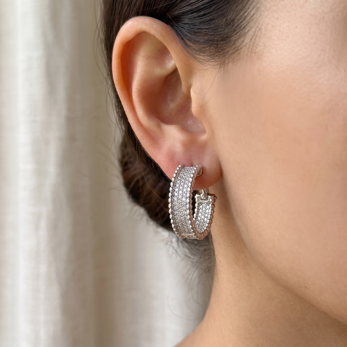 White gold pavé diamond hoop earrings with beaded edges, worn