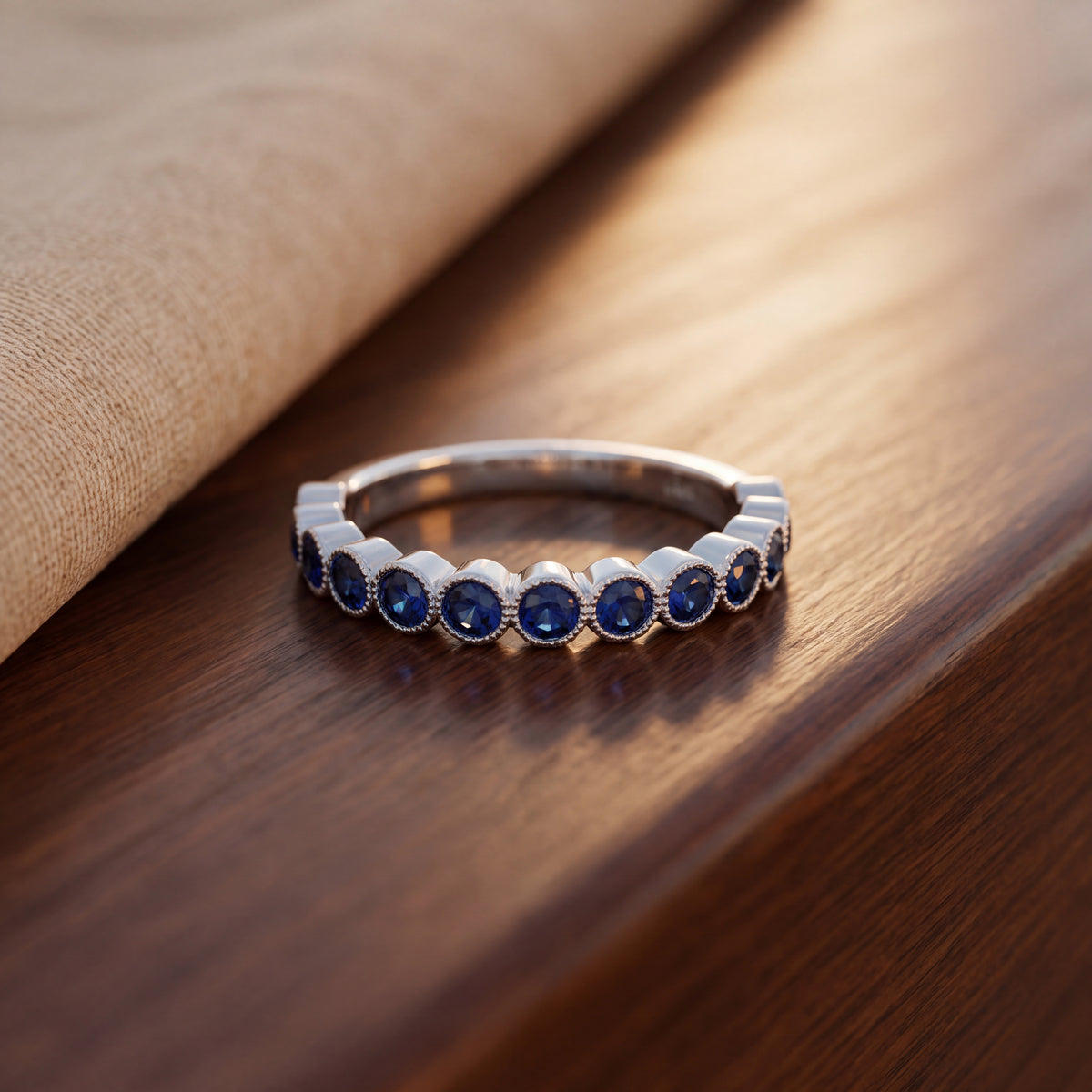 White gold band of round blue sapphires in milgrain bezels