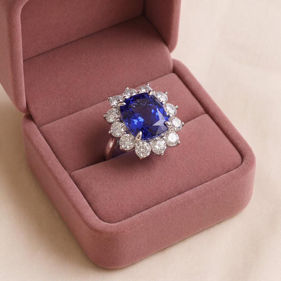 Cocktail ring with a cushion-cut tanzanite in four prongs and a halo of round diamonds, set in white gold