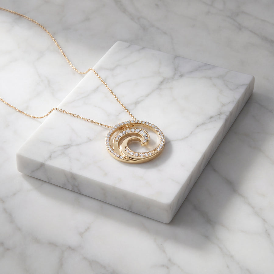 Round yellow gold pendant with a diamond-set breaking wave