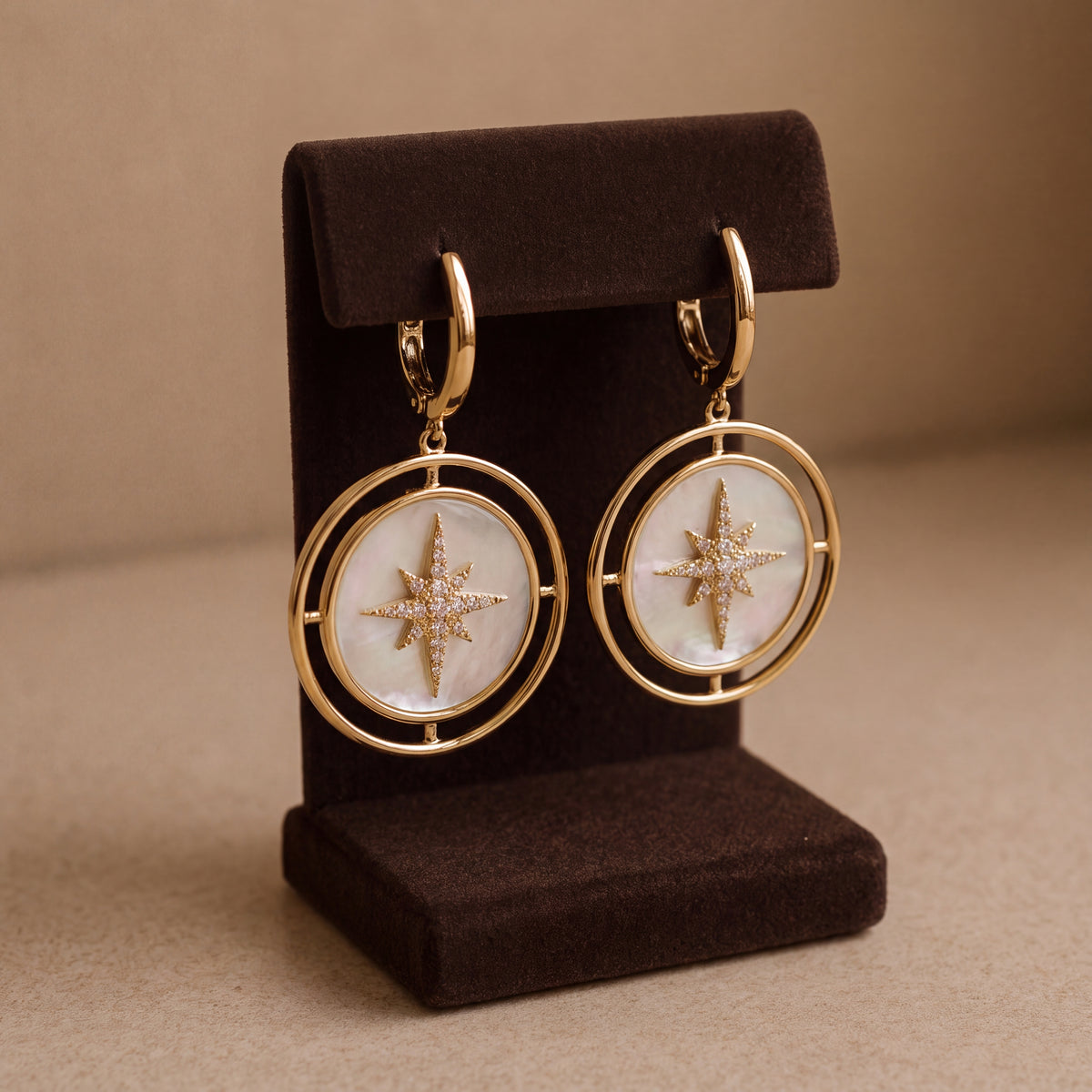 Pair of yellow gold drop earrings with a diamond starburst on white mother of pearl discs inside open gold rings