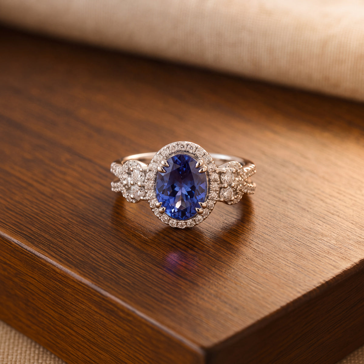 An oval violet-blue stone in a white gold halo ring, on a dark wooden surface.