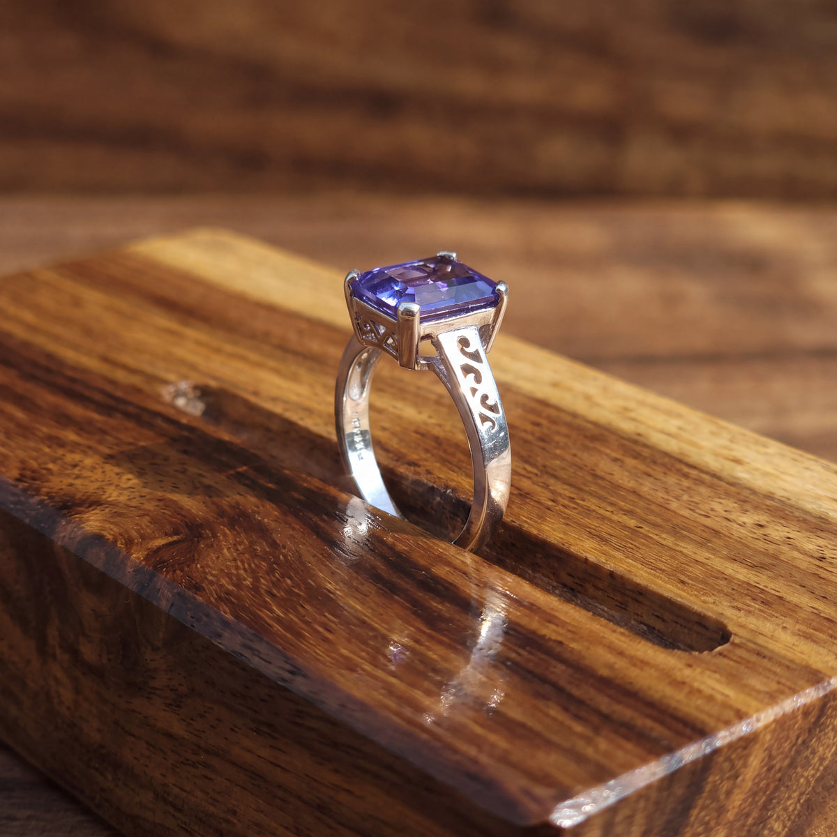 Emerald-cut tanzanite on a white gold band with cut-out scrollwork