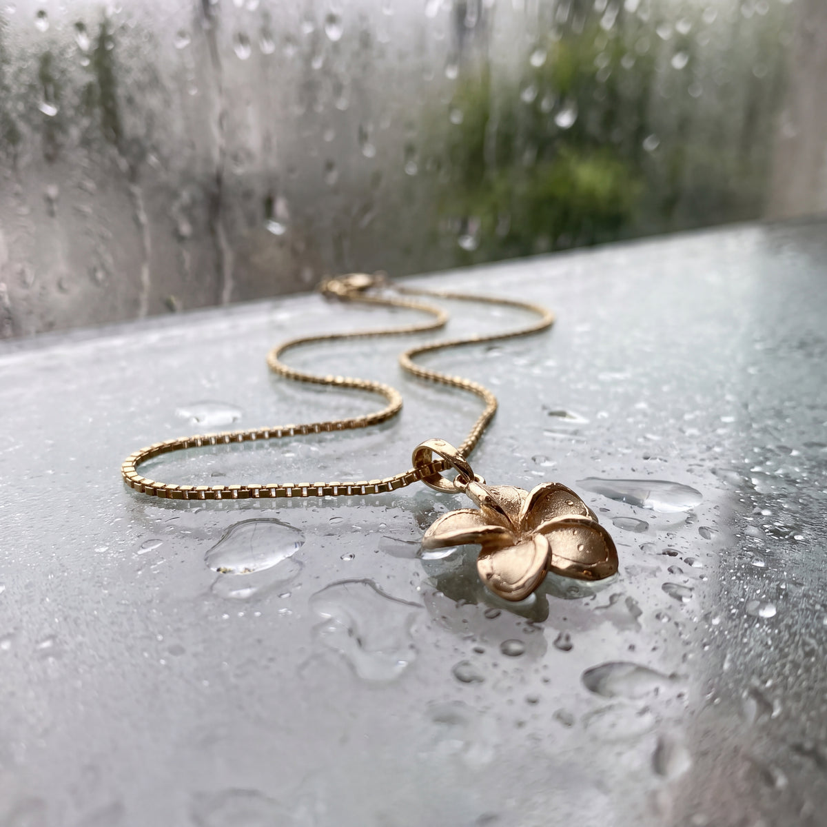 Yellow gold plumeria pendant on a box chain