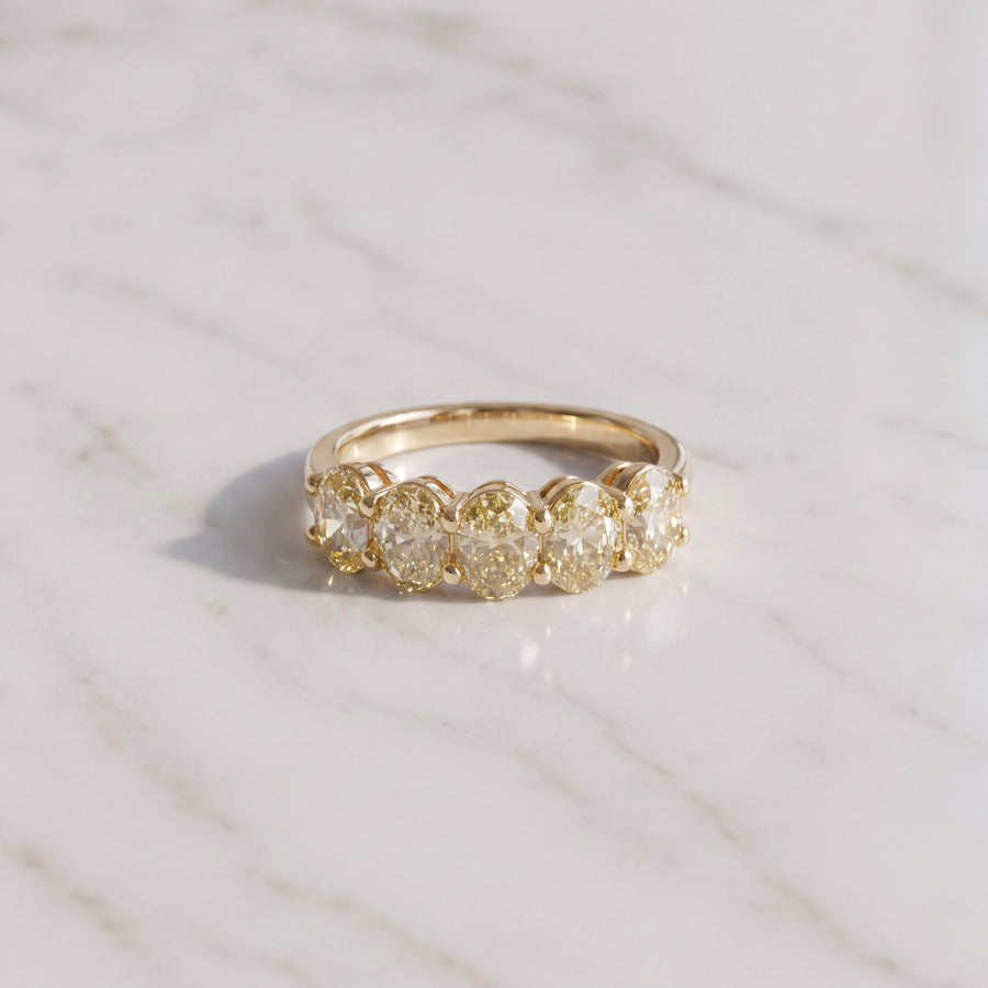 Five oval fancy yellow diamonds side by side on a warm yellow gold band.