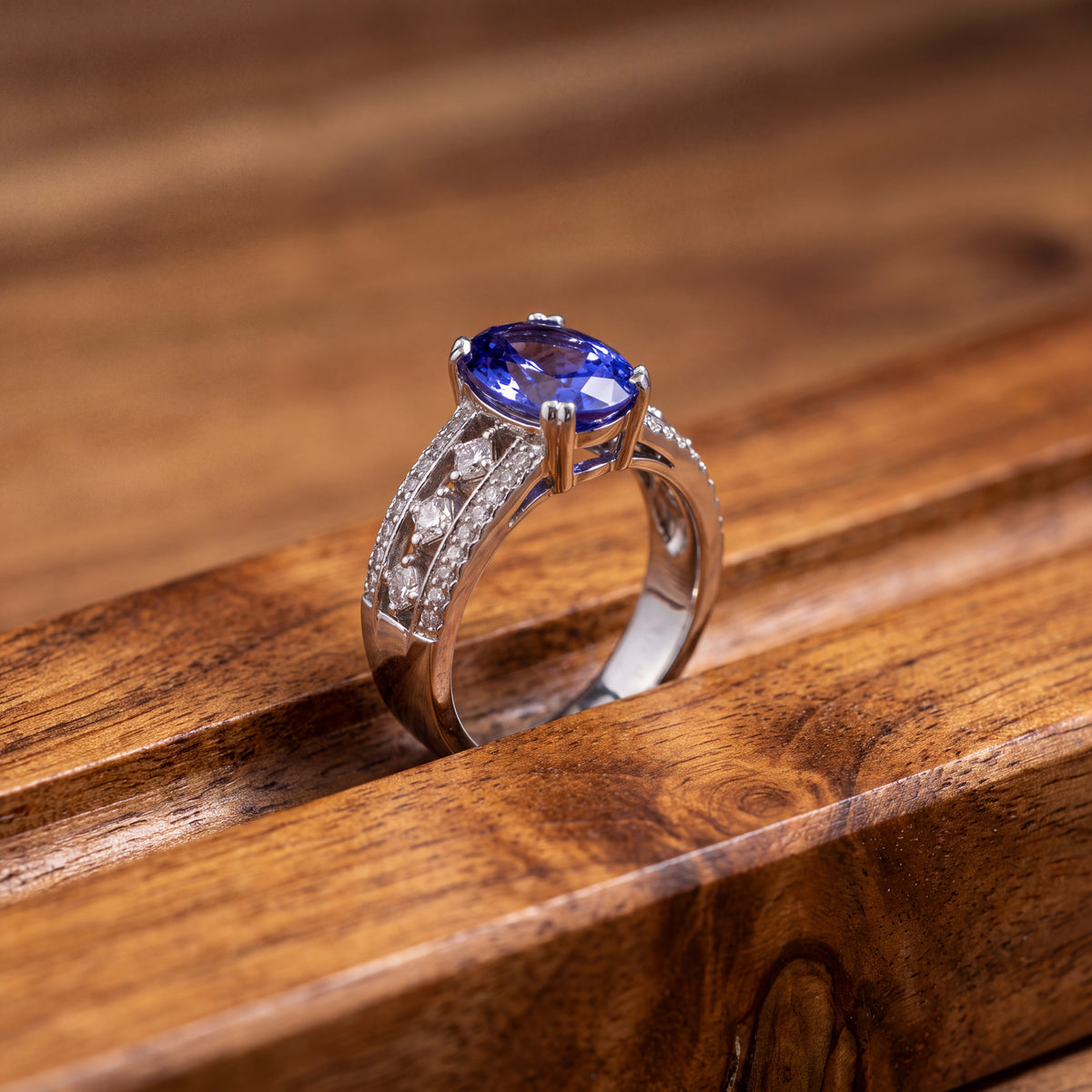 Oval tanzanite ring on a wide white gold band set with rows of diamonds