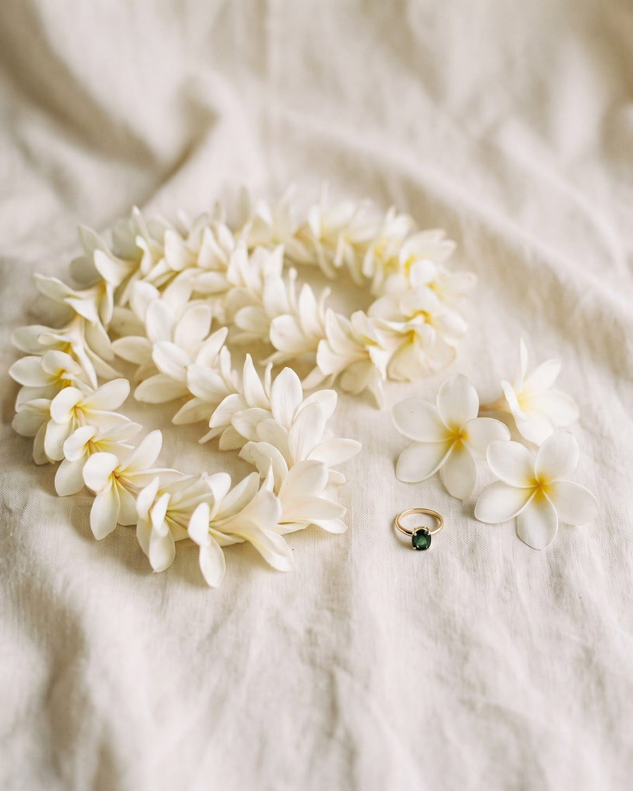 White plumeria lei coiled on ivory linen