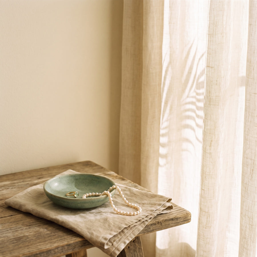 Golden afternoon light through a sheer curtain on a cream wall