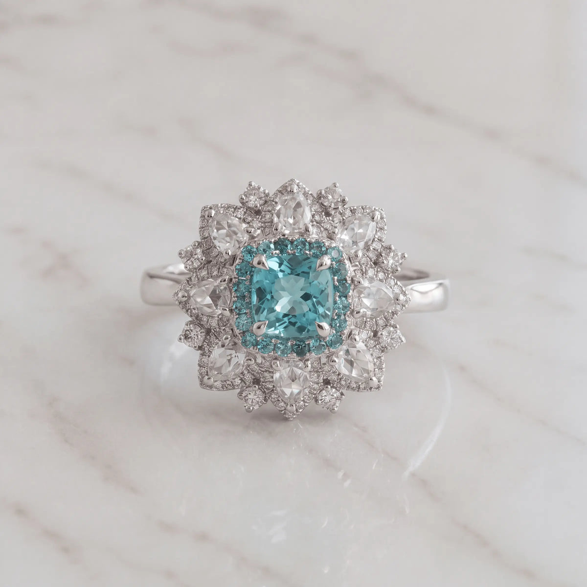 An aqua-center halo ring on pale marble