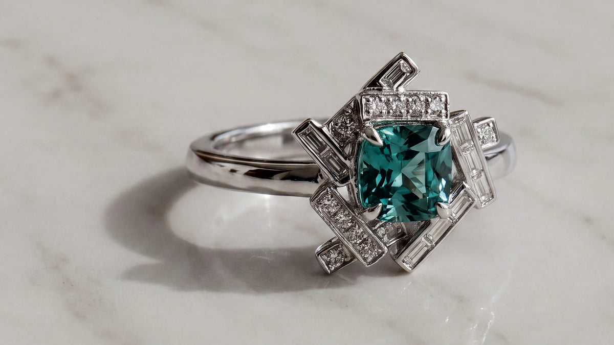 A greenish-blue tourmaline set in a geometric diamond ring in white gold