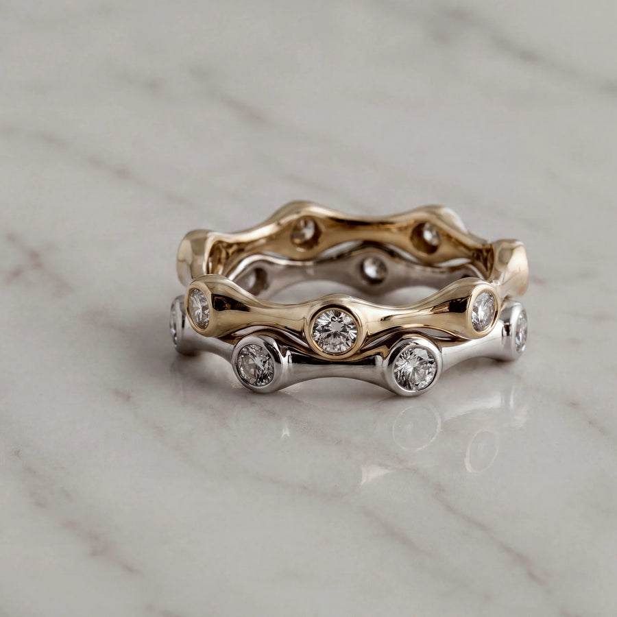 Two wavy stackable rings with bezel-set diamonds, in yellow and white gold