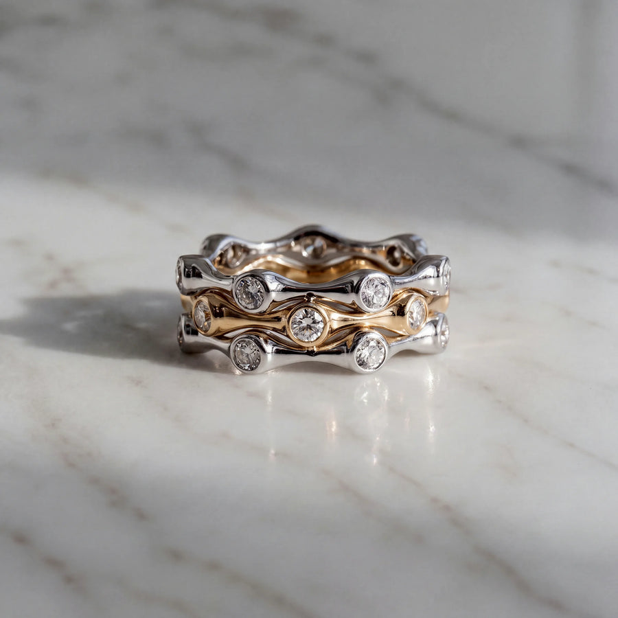 Three stacked bands with bezel-set diamonds, in yellow and white gold