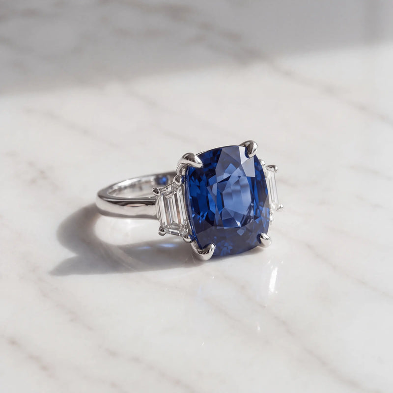 A blue three-stone ring on pale marble