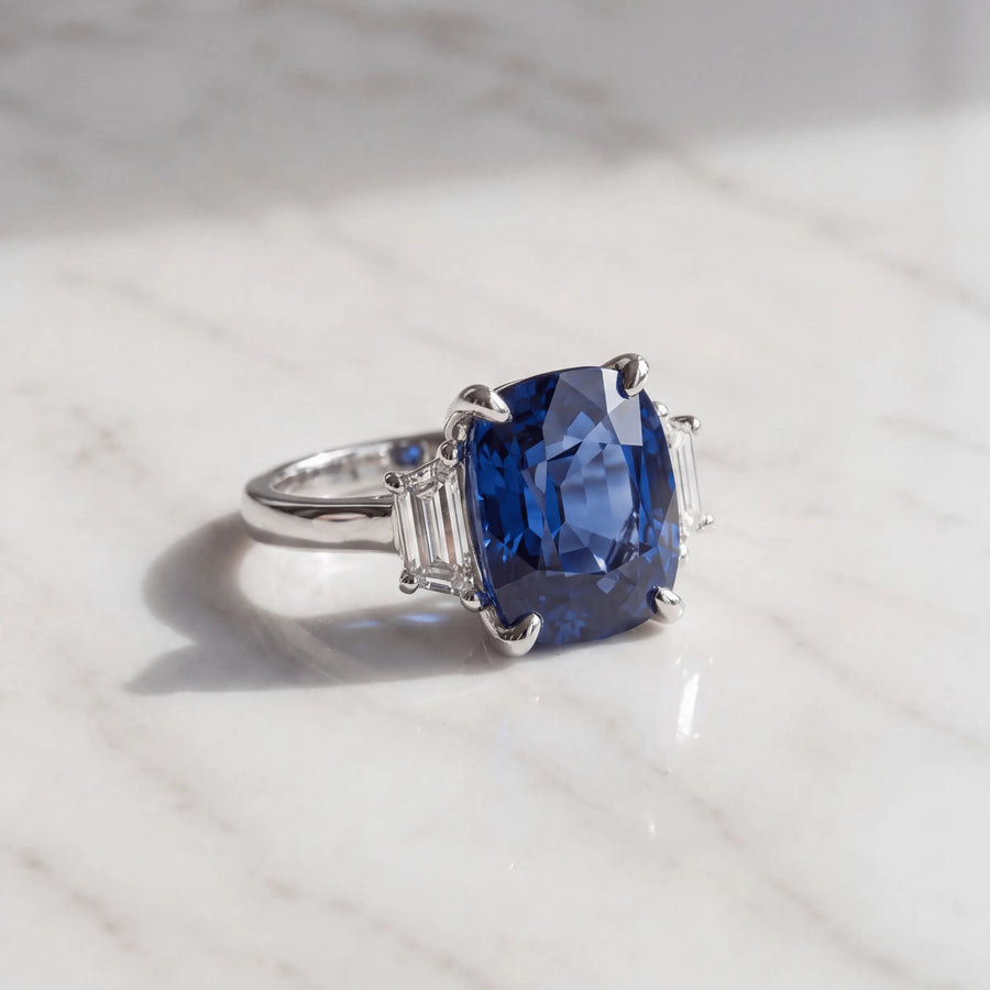 A blue three-stone ring on pale marble
