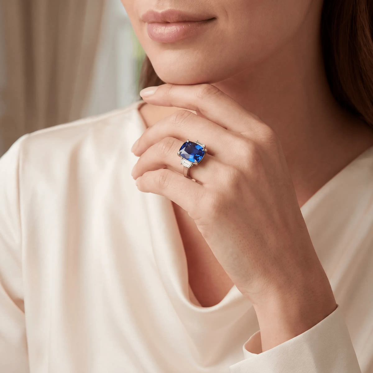 A blue three-stone ring worn on a hand