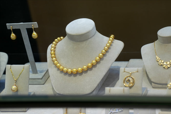 A golden pearl necklace held in the case