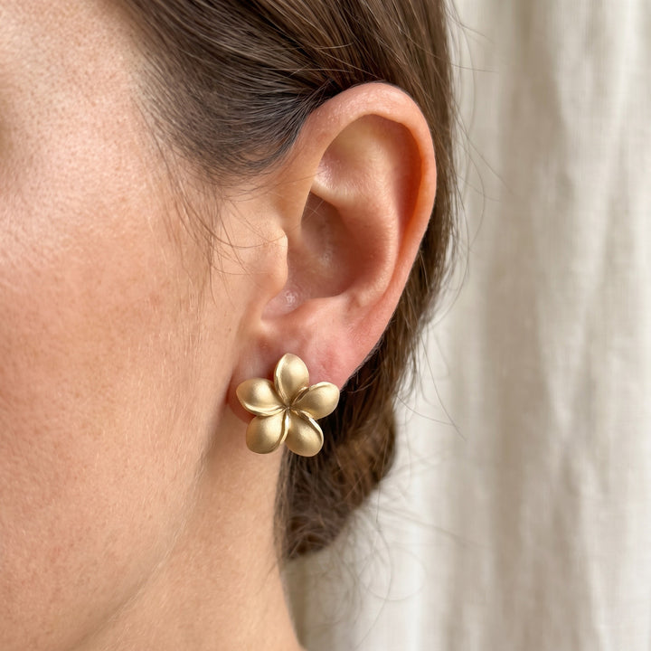 Matte Plumeria Flower Stud Earrings in 14K Yellow Gold, worn