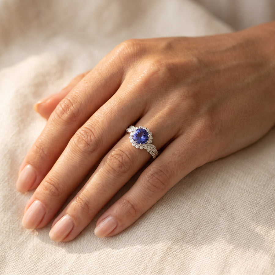 Round tanzanite white gold ring with a diamond halo and twisting diamond-set shoulders, worn