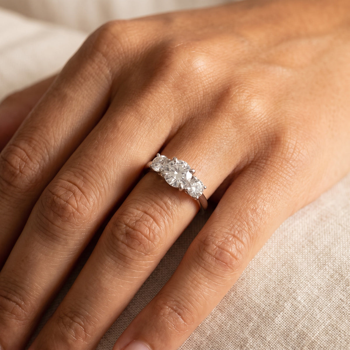 White gold ring with three round diamonds in four-prong settings, worn