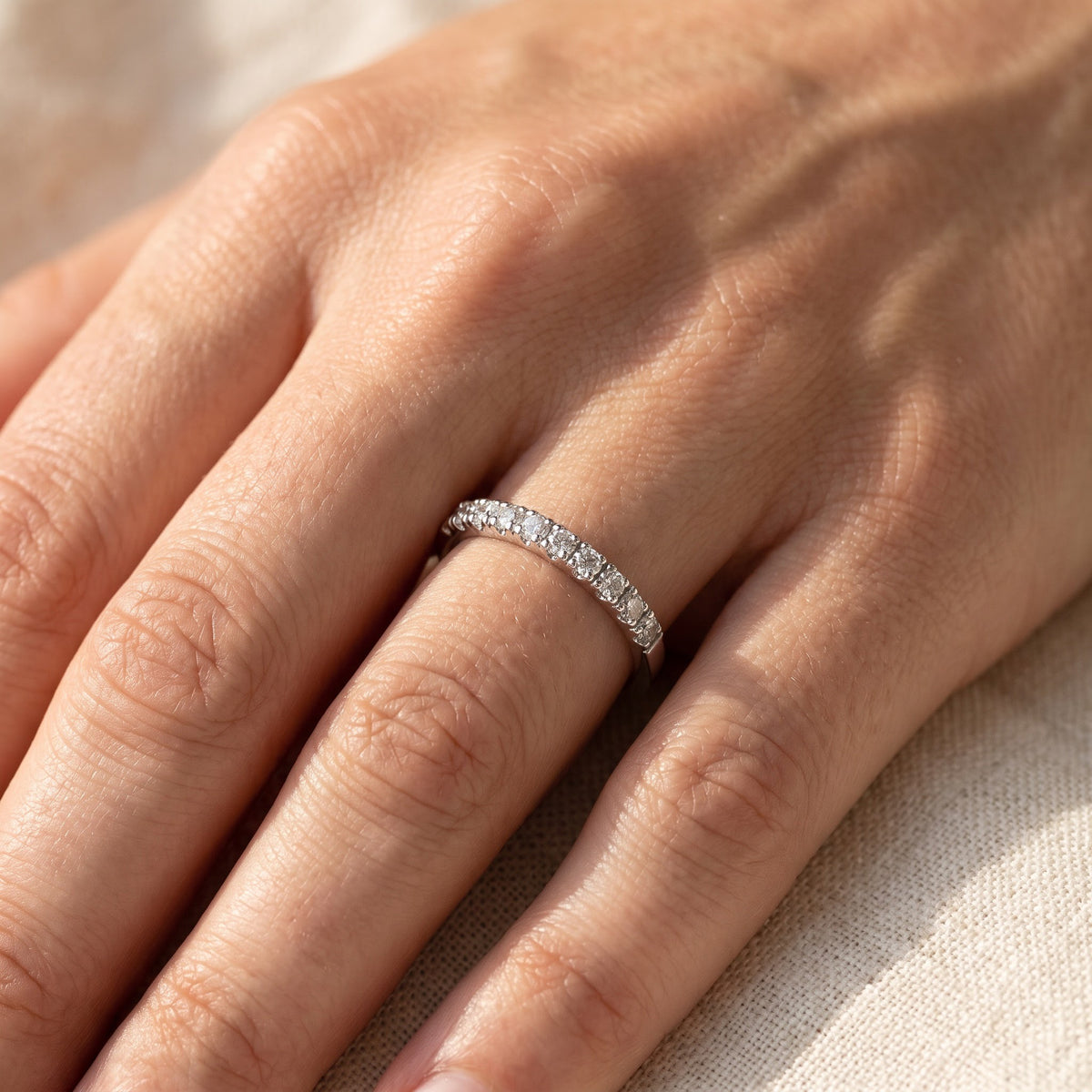 Slim white gold band with a row of round diamonds, worn