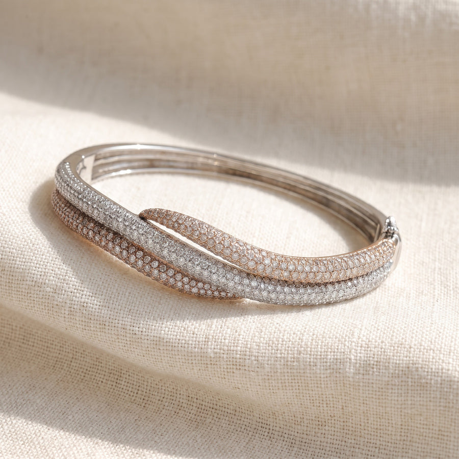 Tri-color gold bangle of intertwined pavé diamond bands with a hinged clasp